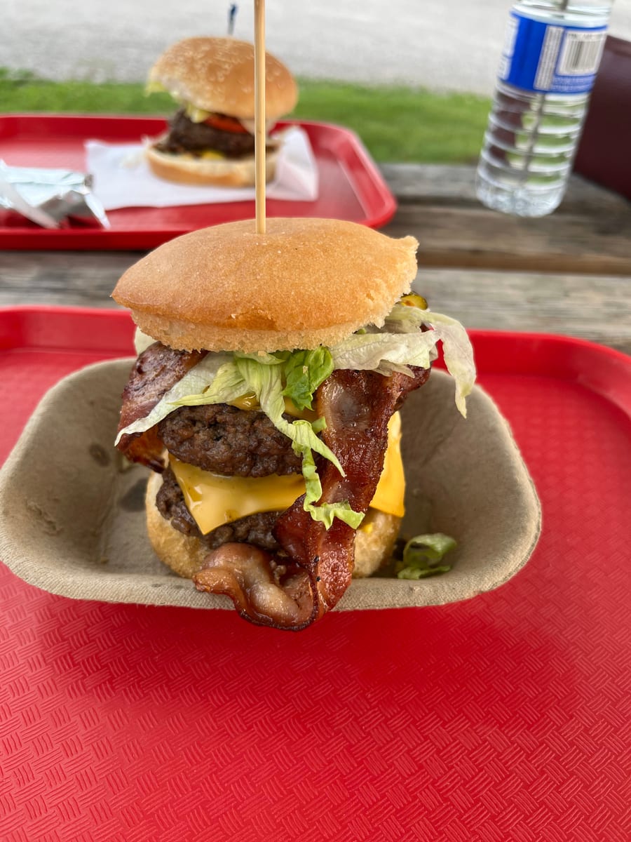 A bacon cheeseburger on a red tray at the picnic tables