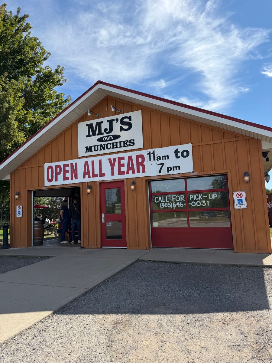 The MJ's Own Munchies building on Lakeshore Road under a blue sky, with the Open All Year sign over the door