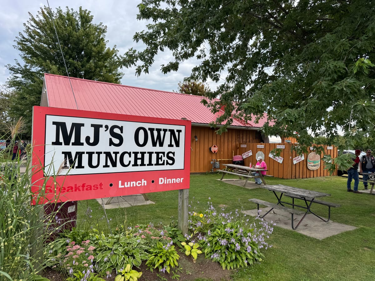 The MJ's Own Munchies roadside sign and picnic tables in the garden