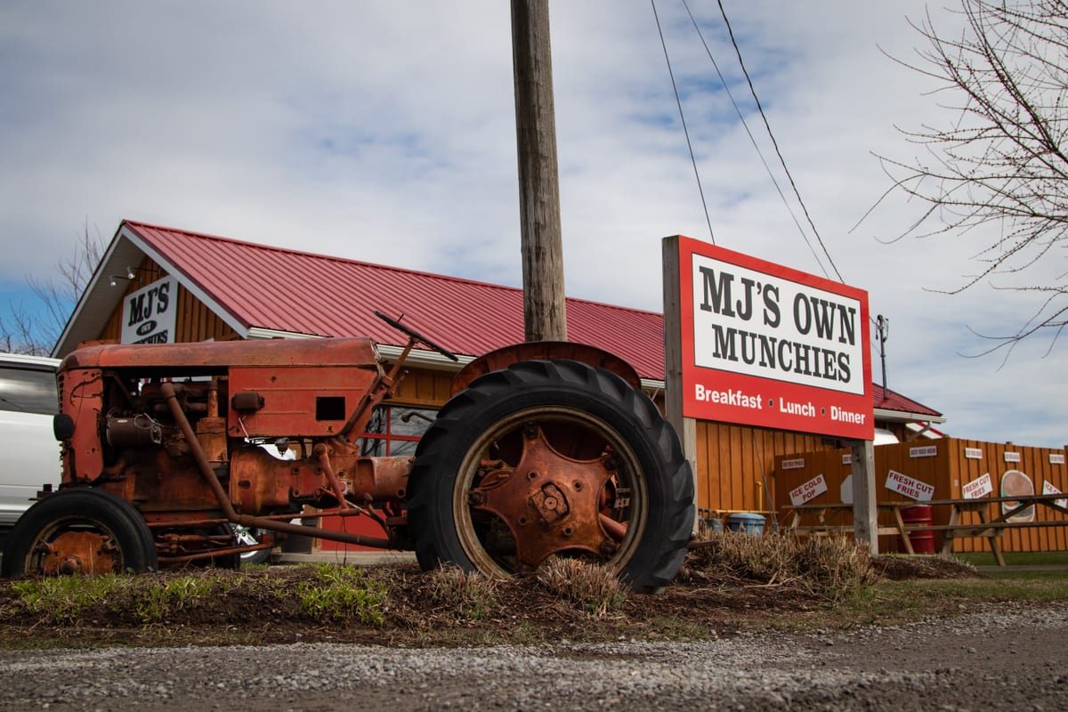 An old red tractor beside the MJ's Own Munchies sign